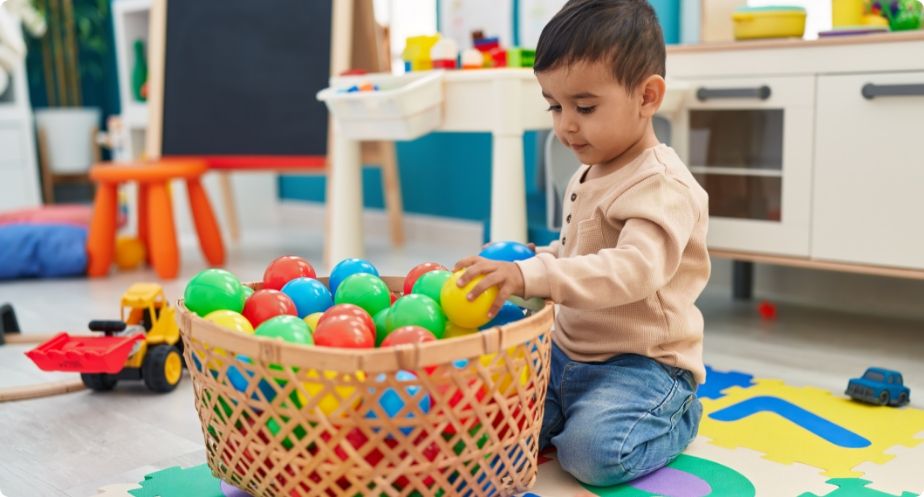 Young child at Bee Smart Preschool Education playing with colorful balls in a learning environment designed to promote coordination, sensory exploration, and early development.